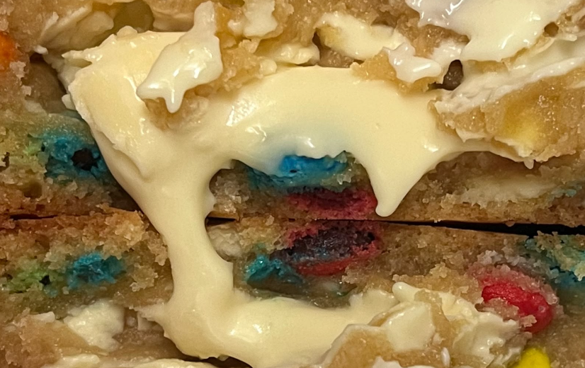 Close up of a loaded cookie with melting white chocolate and colourful candy pieces